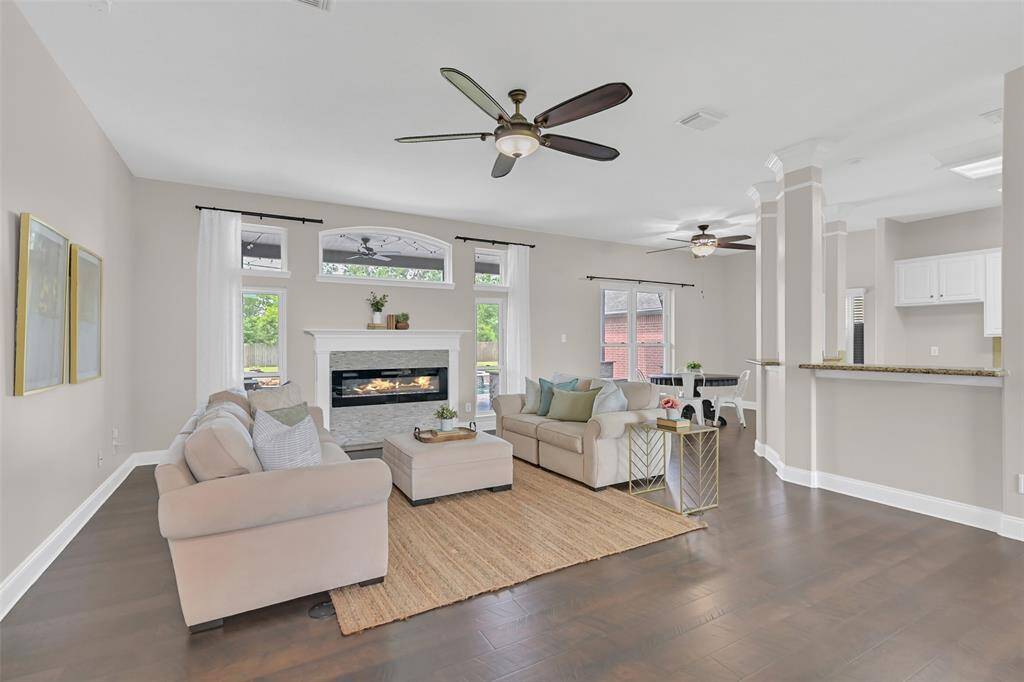 Spacious family room with rich 24+ Pergo wood flooring, a sleek electric fireplace with stacked stone surround, and abundant natural light—designed for comfortable everyday living with a modern, elegant touch.