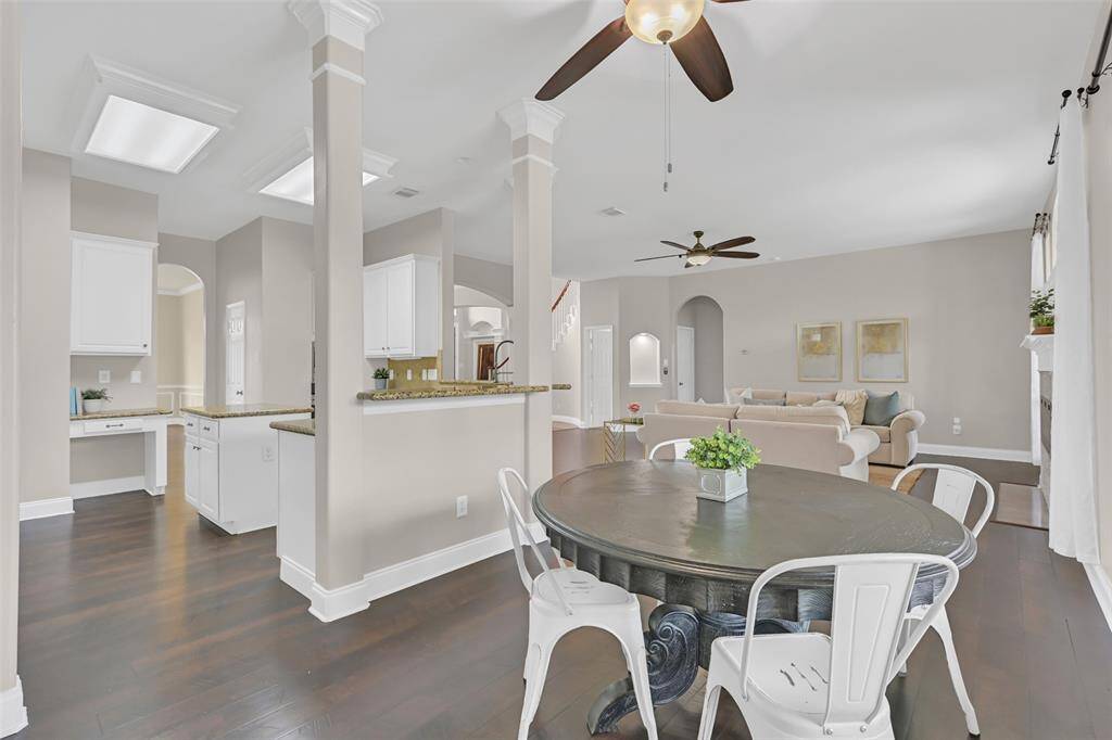 Charming breakfast nook with warm Pergo wood floors and natural light, seamlessly connected to the kitchen by columned openings and a raised granite bar—ideal for casual dining or morning coffee with a view of the backyard oasis!
