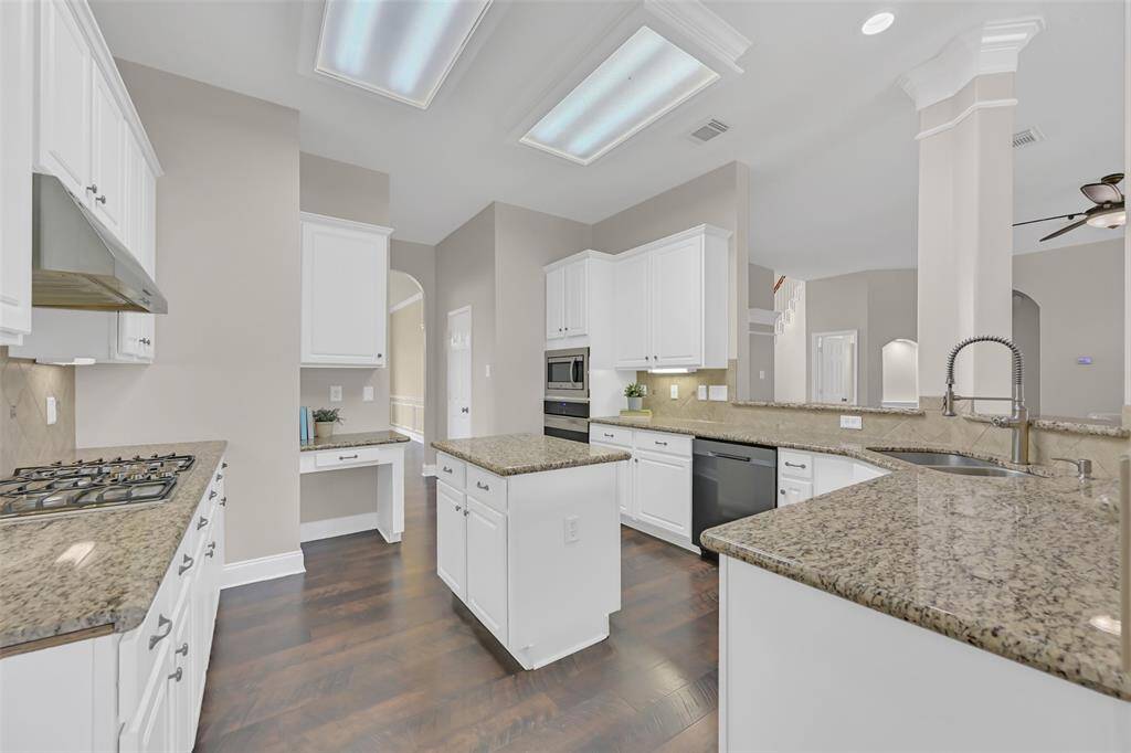 Spacious island kitchen with granite countertops, gas cooktop, built-in desk, white cabinetry, and upgraded pull-down faucet. Open to the living and breakfast areas, this layout is perfect for entertaining or everyday cooking.