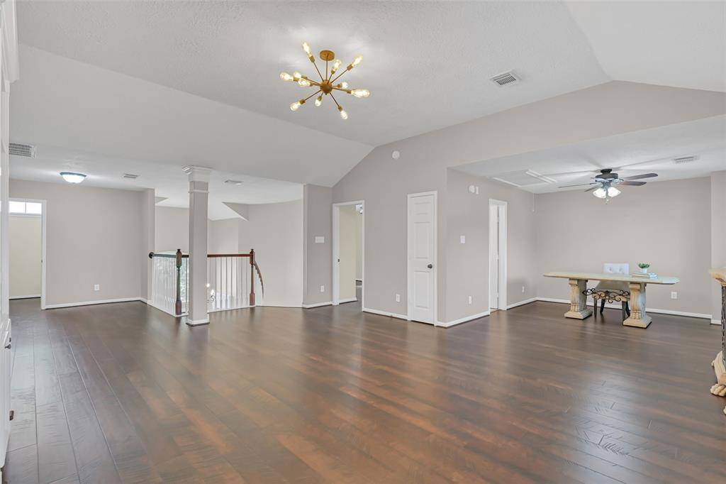 Expansive upstairs game room with rich Pergo 24+ wood-look flooring,modern lighting, and versatile space for a media area, play zone, or home office—an ideal second living area with room to relax or entertain.