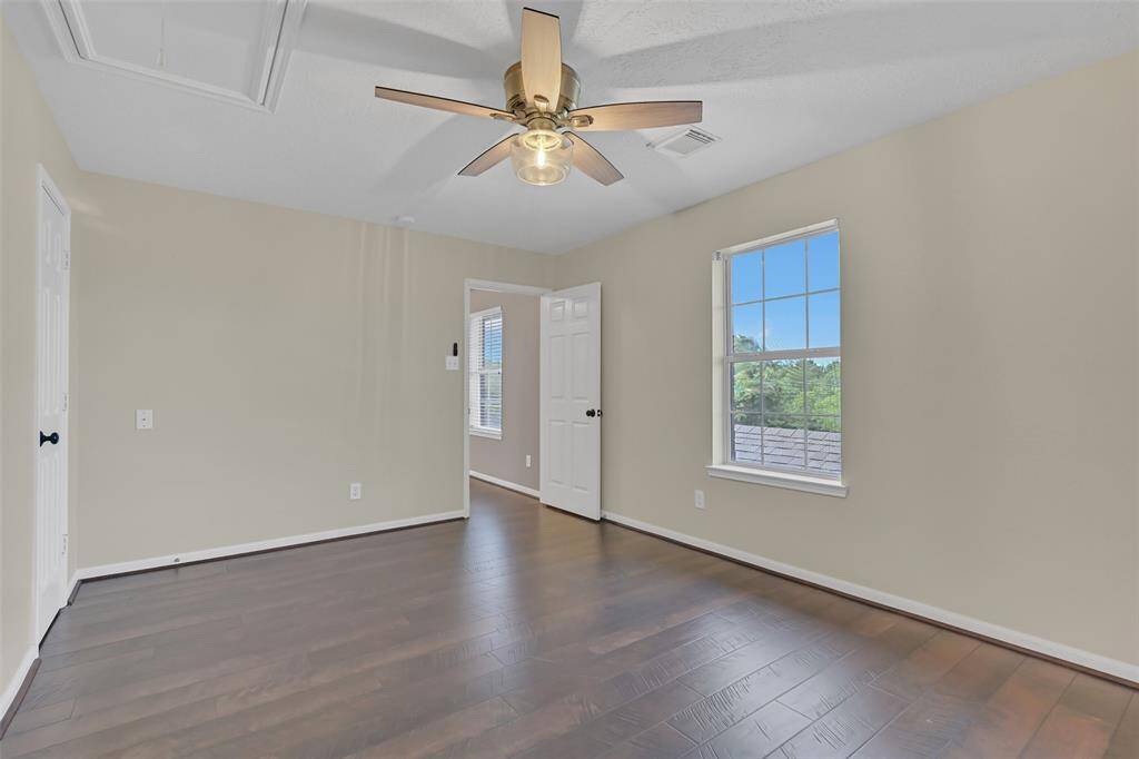 Light-filled secondary bedroom with rich wood-look flooring, a spacious walk-in closet, and direct access to a Jack & Jill style bathroom with private vanities—perfect for shared living with personal space.