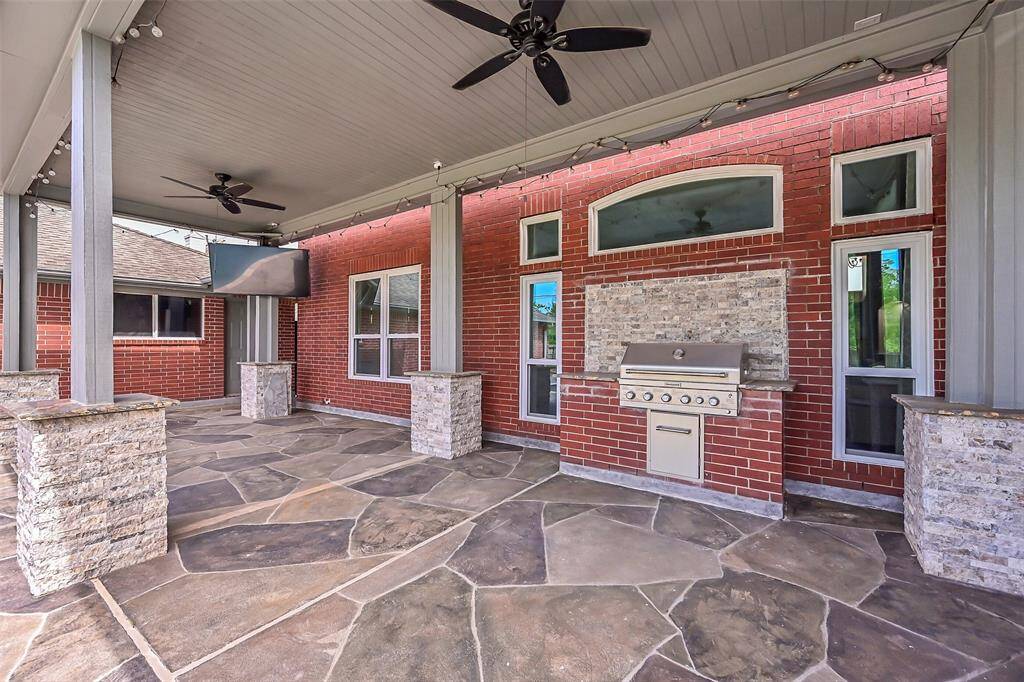 Enjoy year-round outdoor living on the expansive 31'x13' covered patio featuring durable Carvestone flooring, dual ceiling fans, and a custom built-in grilling station added in 2020—perfect for entertaining in style.