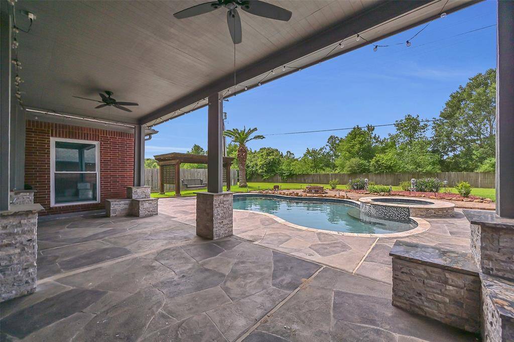 Step out to your private backyard oasis—lush landscaping surrounds a sparkling pool with a raised spa, rock waterfall, and Carvestone decking, all perfectly visible from the extended covered patio for seamless indoor-outdoor living.