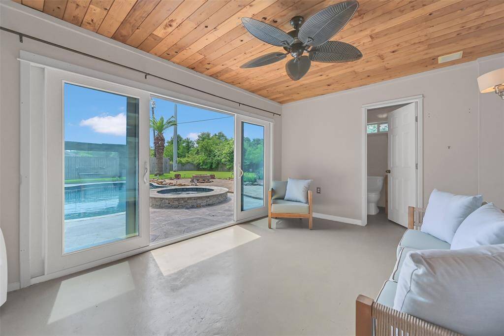 Step inside the 15'x11' cabana, featuring painted concrete floors, a full bathroom, and a charming tongue-and-groove wood ceiling with a tropical-style fan—all with serene views of the pool and firepit. Ideal for a guest suite, gym, or creative retreat.