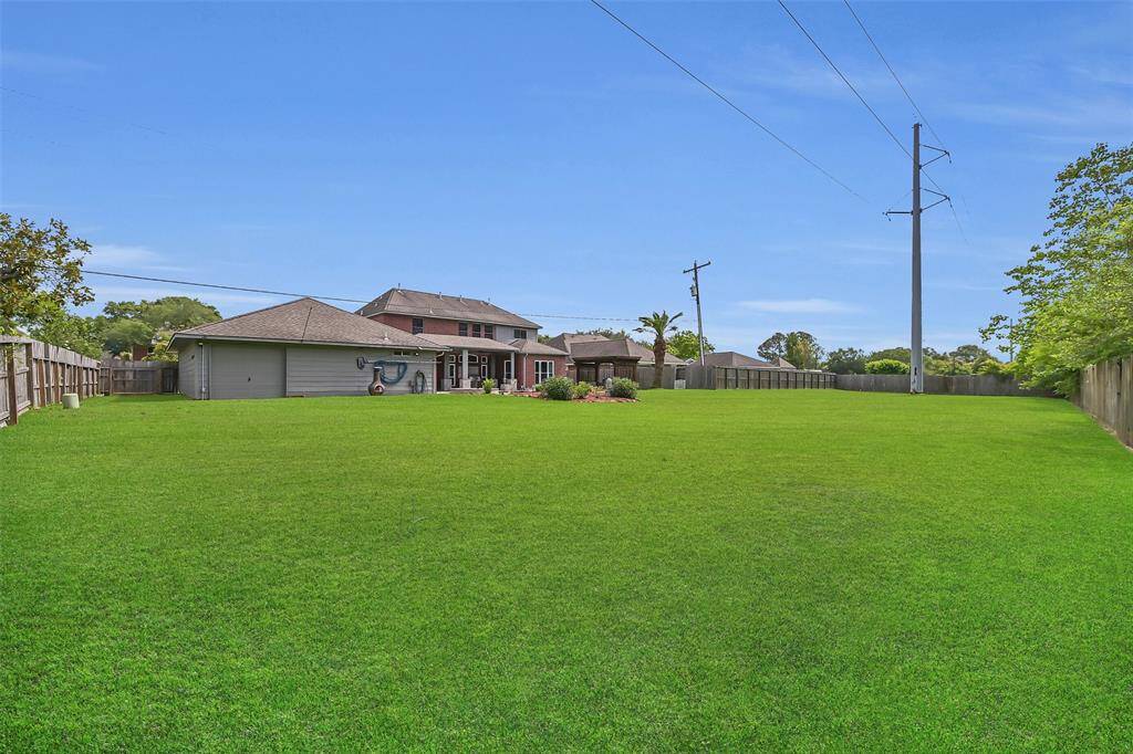 This view showcases the sheer scale of the backyard—a sprawling expanse of green space perfect for sports, play, gardening, or future additions. Whether you envision a workshop, garden beds, a sports field, or just room to roam, this fully fenced 0.58-acre lot offers unparalleled flexibility and privacy.