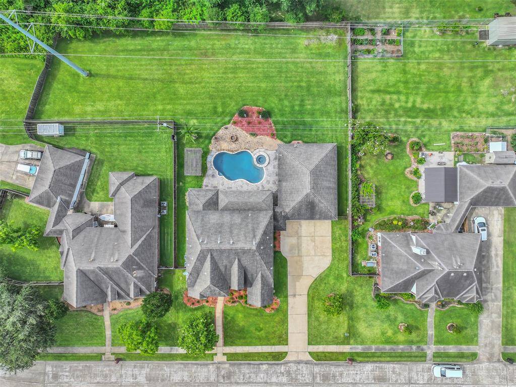 Bird’s-eye view reveals the expansive lot, oversized driveway, and custom-designed pool with spa—perfectly positioned for privacy and entertaining on this rare 0.58-acre parcel in the heart of Friendswood.