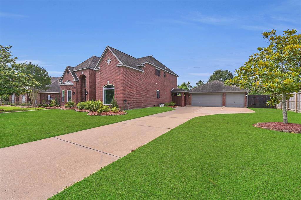 Extended driveway leads to a rare 5-car tandem garage complete with a rear garage door to the backyard—offering ample space for vehicles, storage, or a workshop setup.