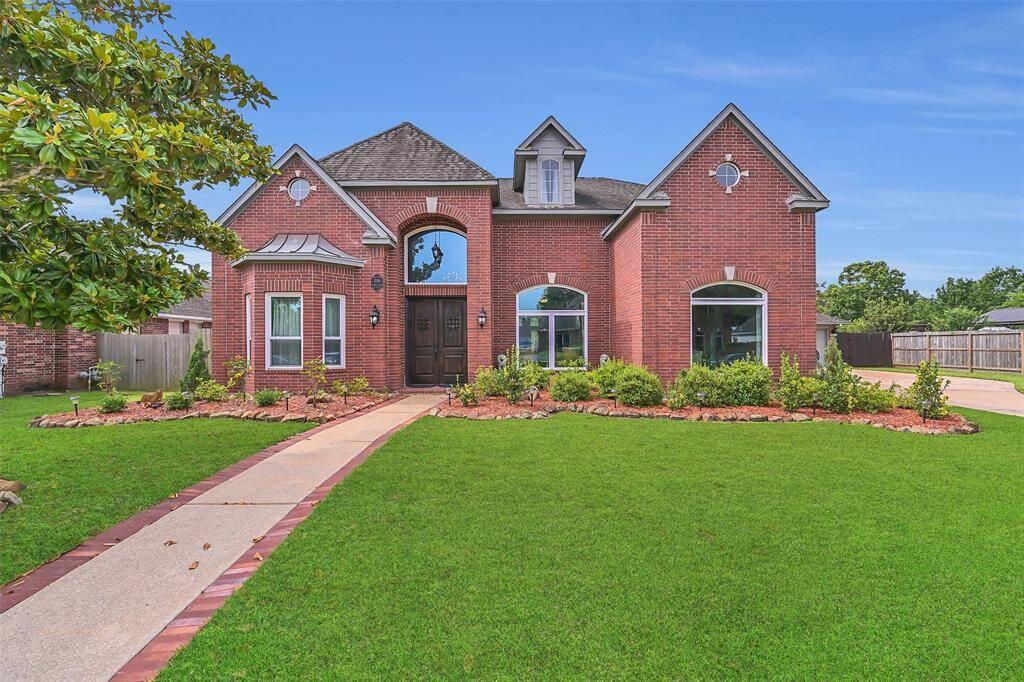 Timeless curb appeal with grand arched entry, classic brick exterior, manicured landscaping, and a brick-trimmed walkway leading to a pair of grand, custom dsigned double doors—setting the tone for elegant living in the prestigious Boca Raton community.