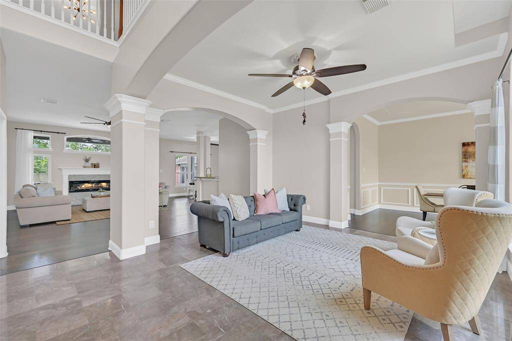 Sophisticated formal living space with polished marble tile floors, soaring ceilings, and graceful archways accented by columned detailing—offering a seamless flow into the dining and main living areas.