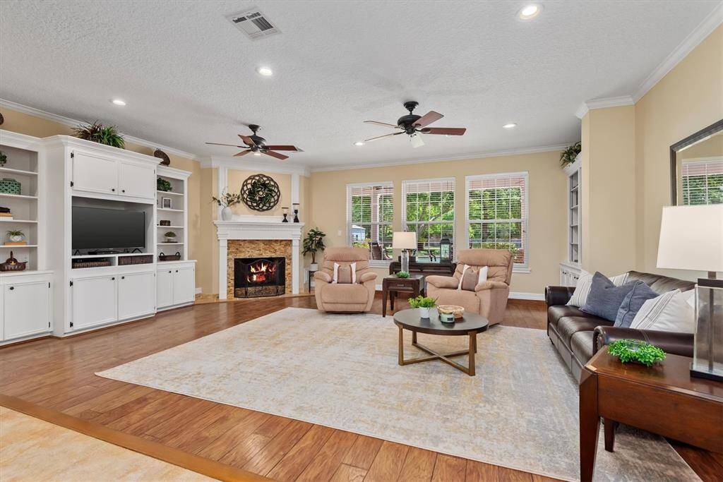 This spacious living room featuring a cozy fireplace, built-in shelving, and large windows with views of the backyard—ideal for relaxing or gathering with family and friends.