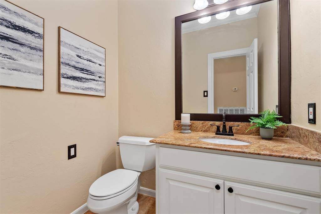 The conveniently located powder bath with granite countertop and framed mirror is perfect for guests.