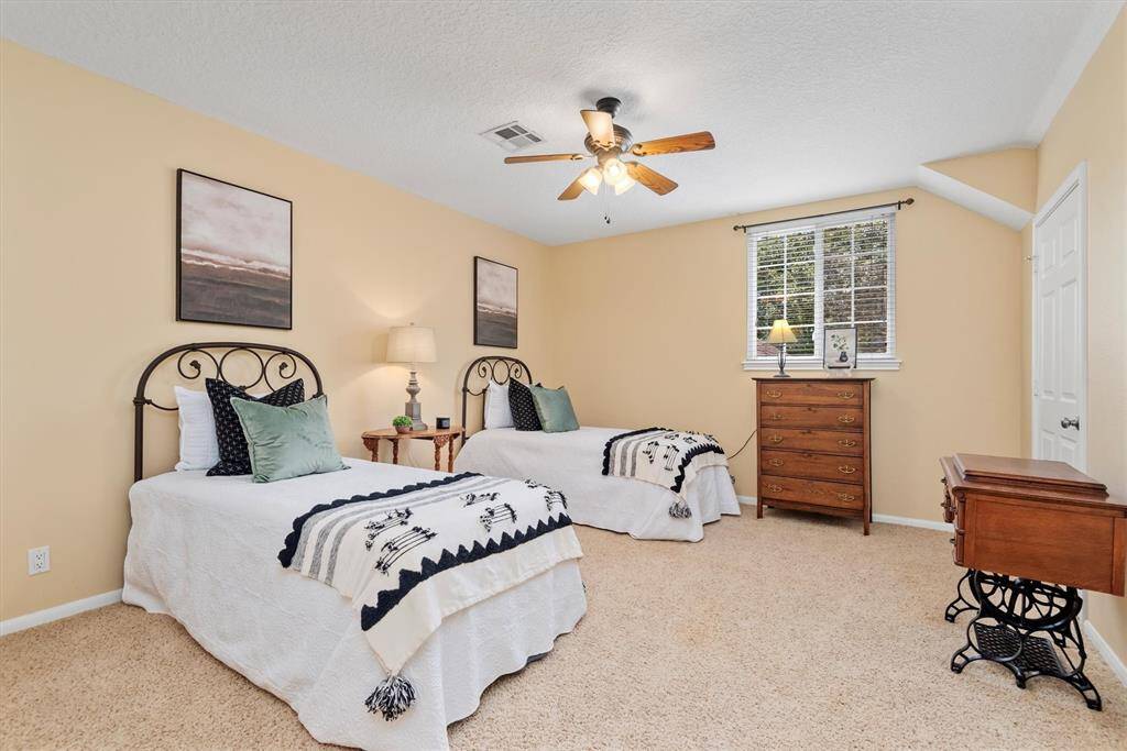 Upstairs Bedroom 1 -Spacious secondary bedroom with neutral tones, ceiling fan, and large window—perfect for guests or family members.