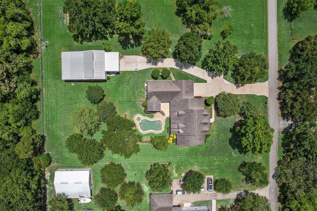 Aerial view of this stunning 1.5-acre property featuring a custom home, sparkling pool, oversized barn, detached garage, and expansive green space—offering privacy and room to live, work, and play.