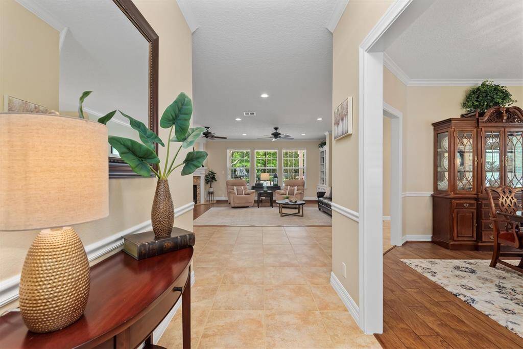 Step inside to a welcoming entryway with views into the spacious living area and formal dining, featuring crown molding and natural light.