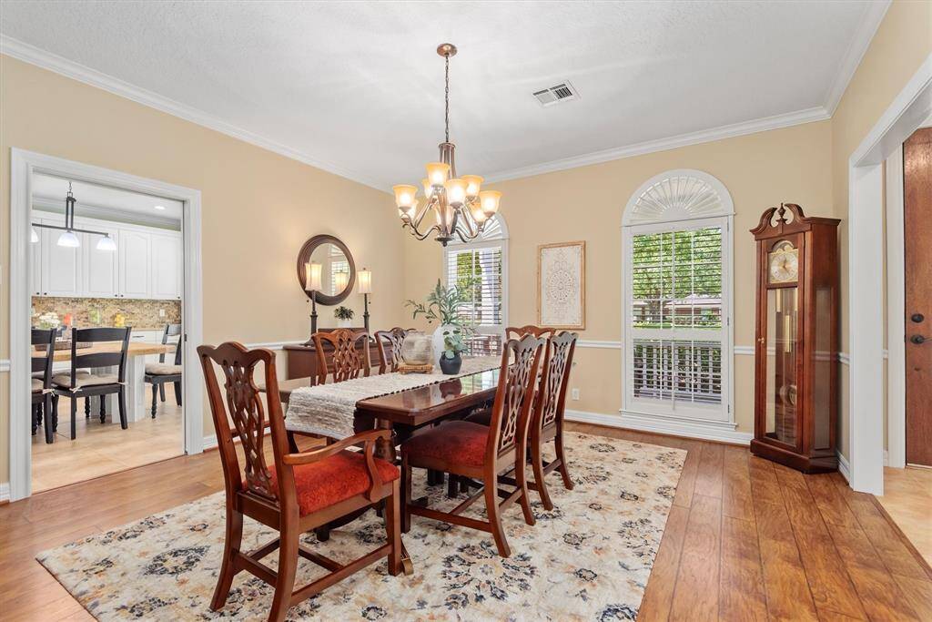 The formal dining room offers wood flooring, crown molding, and large windows, creating the perfect space for hosting family and friends.