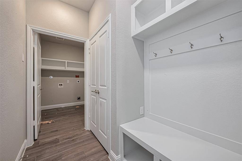 This inviting space features a practical mudroom with built-in hooks and a bench, seamlessly leading to a spacious laundry room. Perfect for organization and convenience.