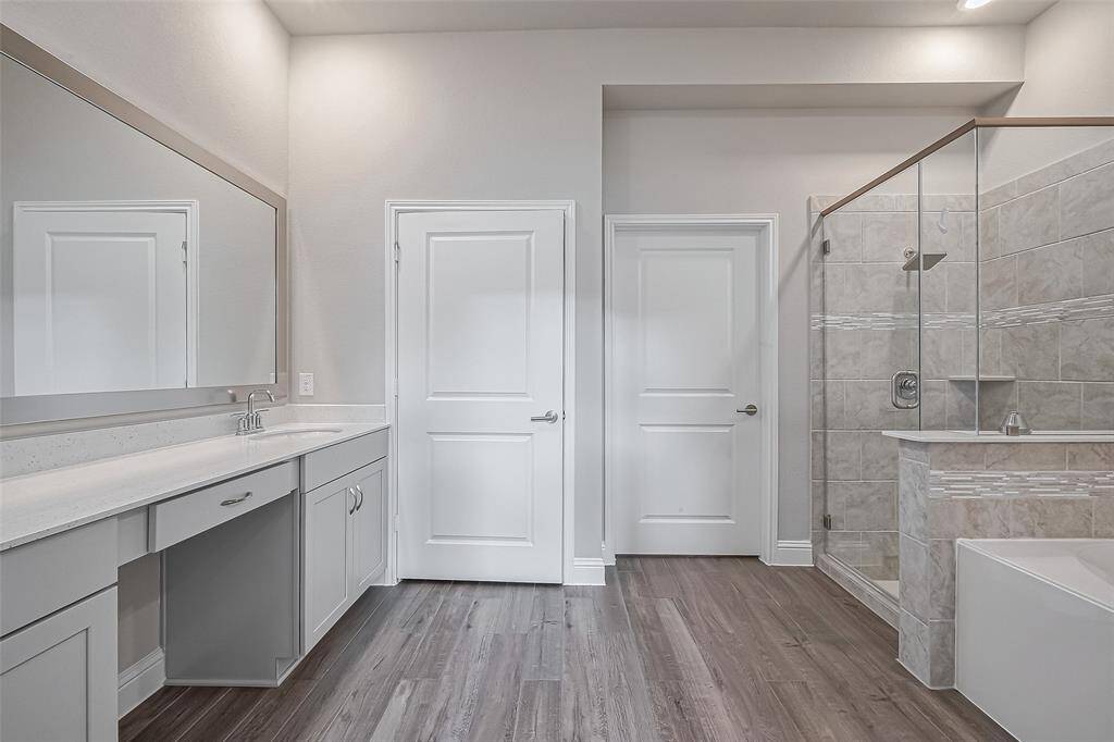This modern bathroom features elegant tile work, a spacious glass-enclosed shower, and a double vanity with ample storage. The neutral tones and high-quality finishes create a serene and inviting atmosphere.