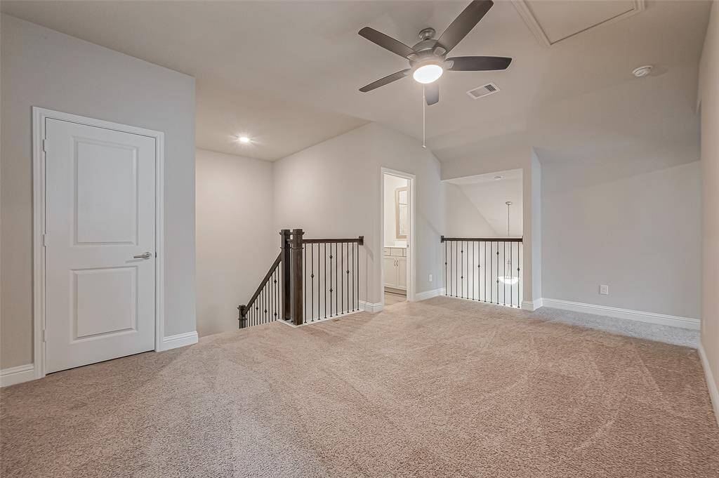 This inviting Gameroom features plush carpeting, a modern ceiling fan, and elegant railing details, offering a cozy and stylish area perfect for relaxation or entertainment.