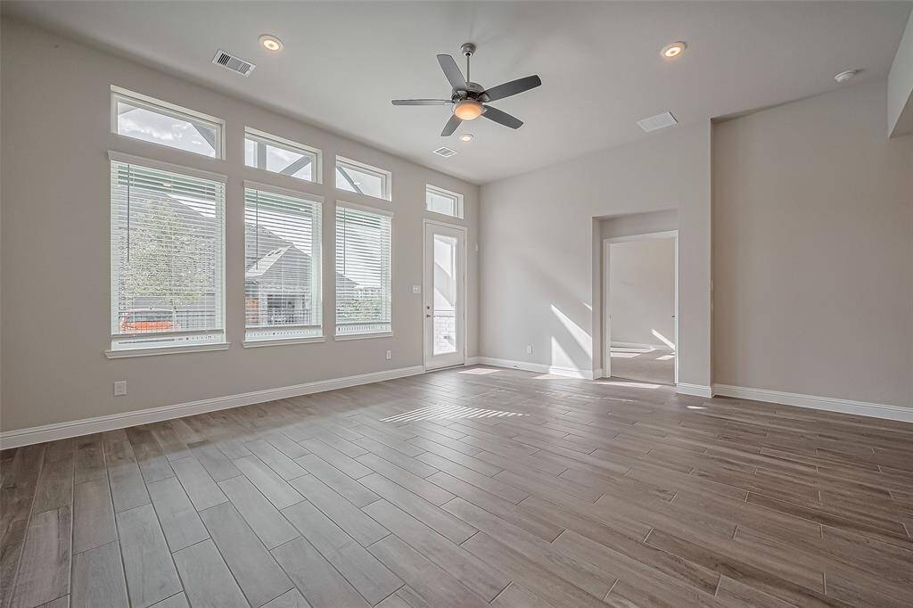Bright and spacious living area featuring large windows for abundant natural light, sleek tile flooring, and a modern ceiling fan. Perfect for relaxation and entertaining.