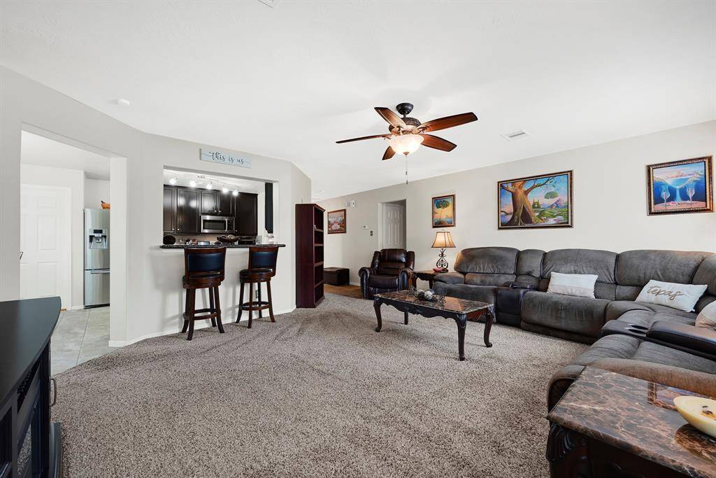 Spacious living room featuring ceiling fans and a cozy bar area, perfect for entertaining.