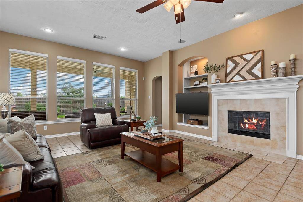 The living area is filled with natural light from the large windows that offer beautiful views of the backyard and sparkling pool.