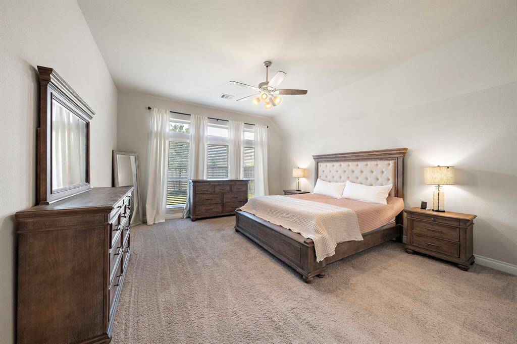 Enjoy peace and privacy in the primary bedroom, highlighted by a wall of windows and soft natural light.