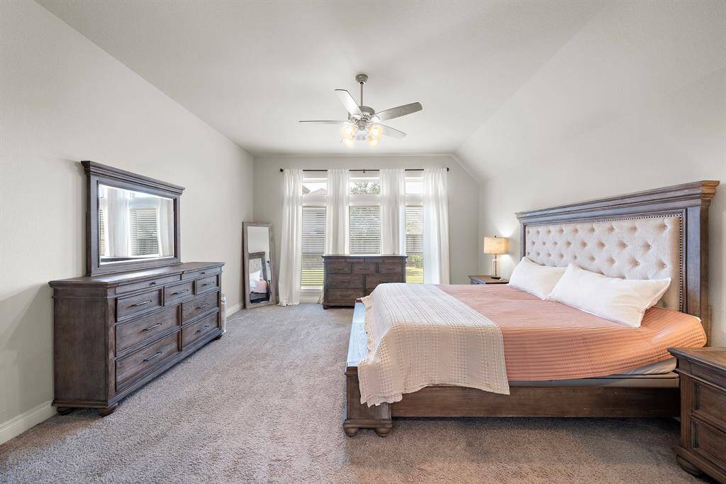 Spacious retreat with soft carpet underfoot for cozy comfort. Floor-to-ceiling windows overlook the backyard, filling the room with natural light.