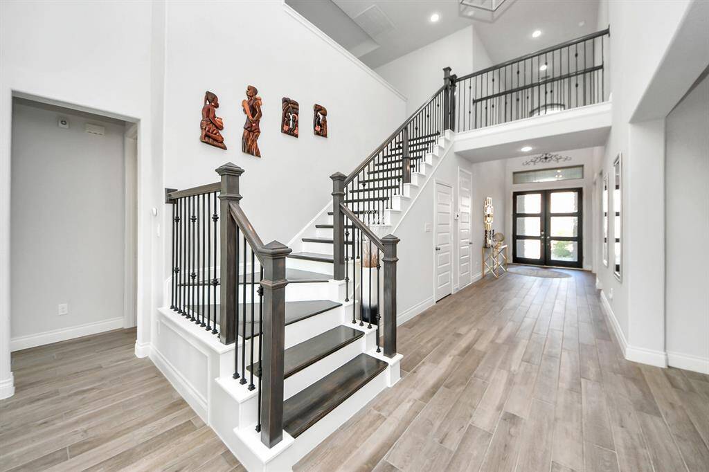 The staircase features sleek, carpet-free steps and wrought iron spindles, adding a modern touch and enhancing the open feel of the space.