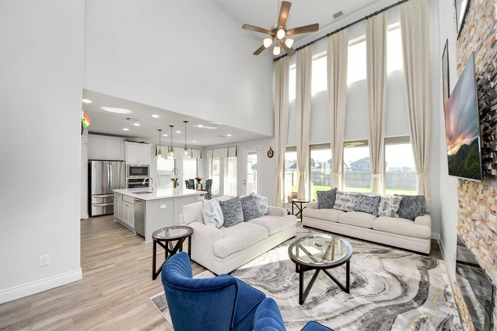 The living room boasts soaring ceilings and expansive windows that flood the space with natural light.