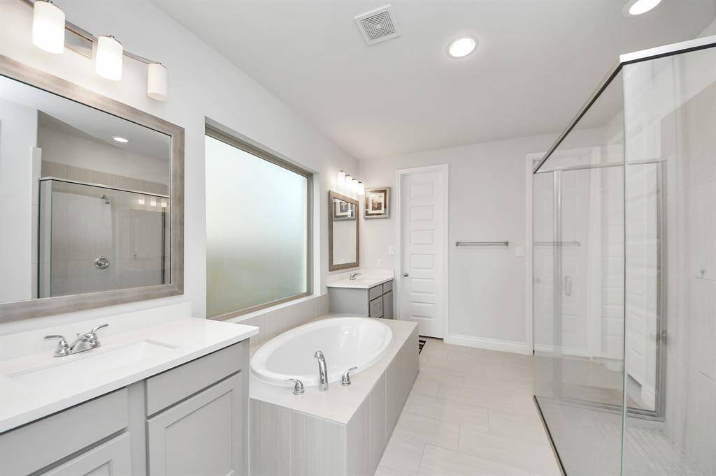 The primary bathroom includes dual vanities, soaker tub, and extended shower.