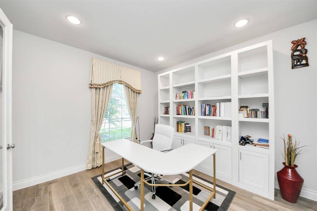 The office is located at the front of the home, with a large window and built in cabinets.
