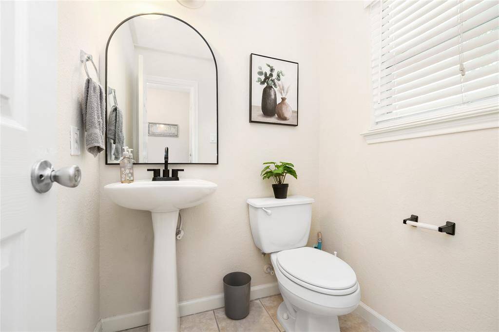 This downstairs half bathroom combines sleek design with convenience, featuring a clean layout and an elegant arched mirror—perfect for guests and everyday use.