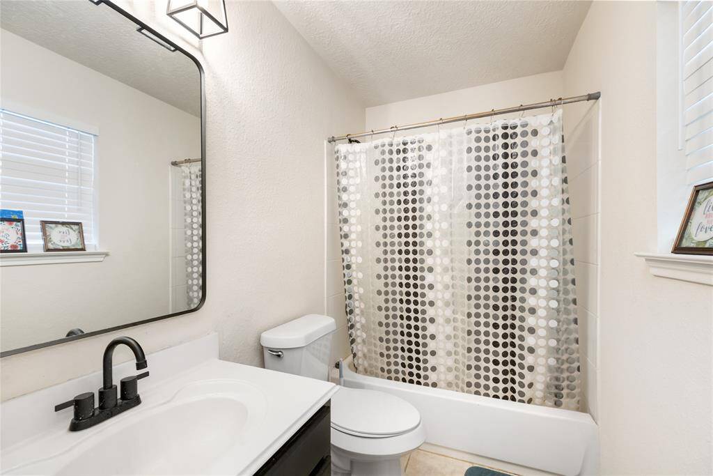 A sleek and clean design highlights this full bath, featuring a shower/tub combination and a stylish black-framed mirror for a modern touch.