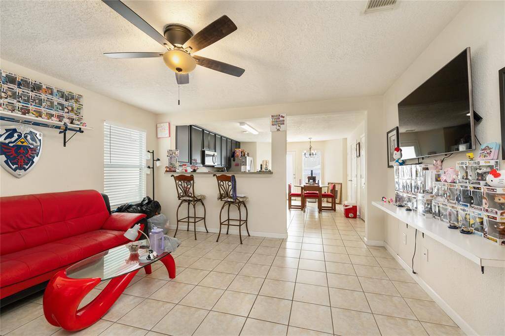 This spacious living area offers an open-concept feel, with a breakfast bar-style pony wall providing a seamless connection to the kitchen—perfect for everyday living and easy entertaining.