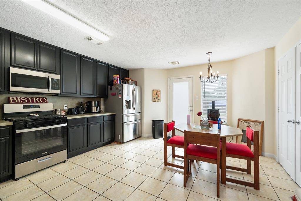 Sleek black cabinetry and abundant storage create a modern, functional kitchen space, while the bright breakfast nook with large windows invites natural light for casual dining.