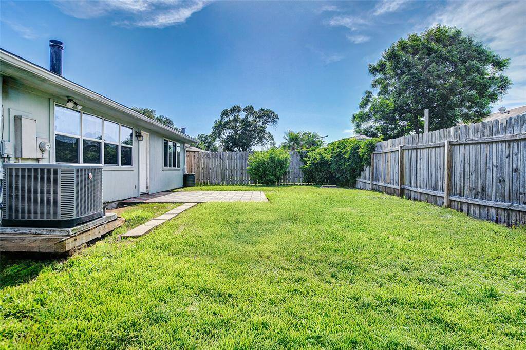 Spacious backyard with lush grass, a paved patio area, and a privacy fence. Come make it your own!