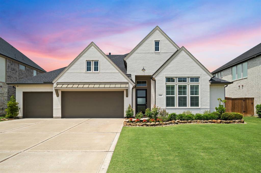 A full view of the home reveals its symmetrical façade, oversized driveway, and thoughtfully designed landscape beds. The elevation combines timeless brickwork with contemporary finishes for a striking presence.