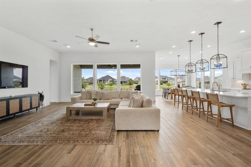 Continuing from the foyer, you’re welcomed into a stunning open-concept living space that seamlessly blends the living room, kitchen, and dining areas. Expansive picture windows surround the space, flooding it with natural light and offering captivating views of the serene lake beyond.