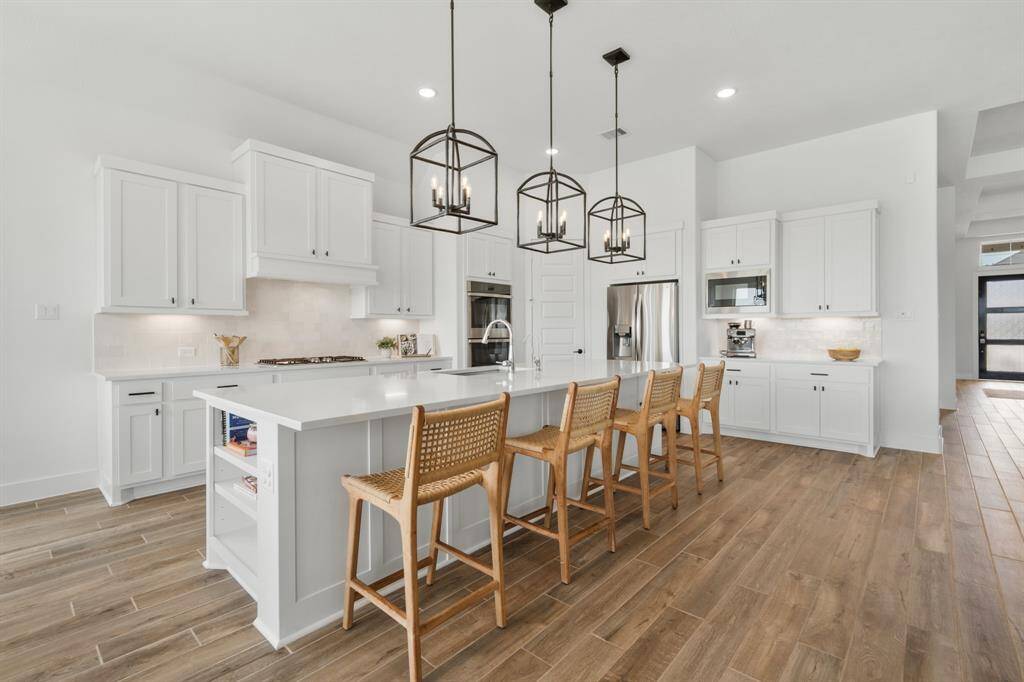 Additional features include stainless steel double ovens and a built-in microwave for culinary convenience. The kitchen is completed with a sleek Luxart stainless steel undermount sink paired with a chrome Delta Essa single-handle pull-down faucet.