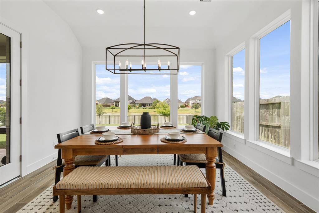 Just off the kitchen, the elegant dining area is illuminated by a striking Pottery Barn iron chandelier. Surrounded by six picture windows, the space is bathed in natural light, creating a warm and inviting atmosphere for memorable meals.