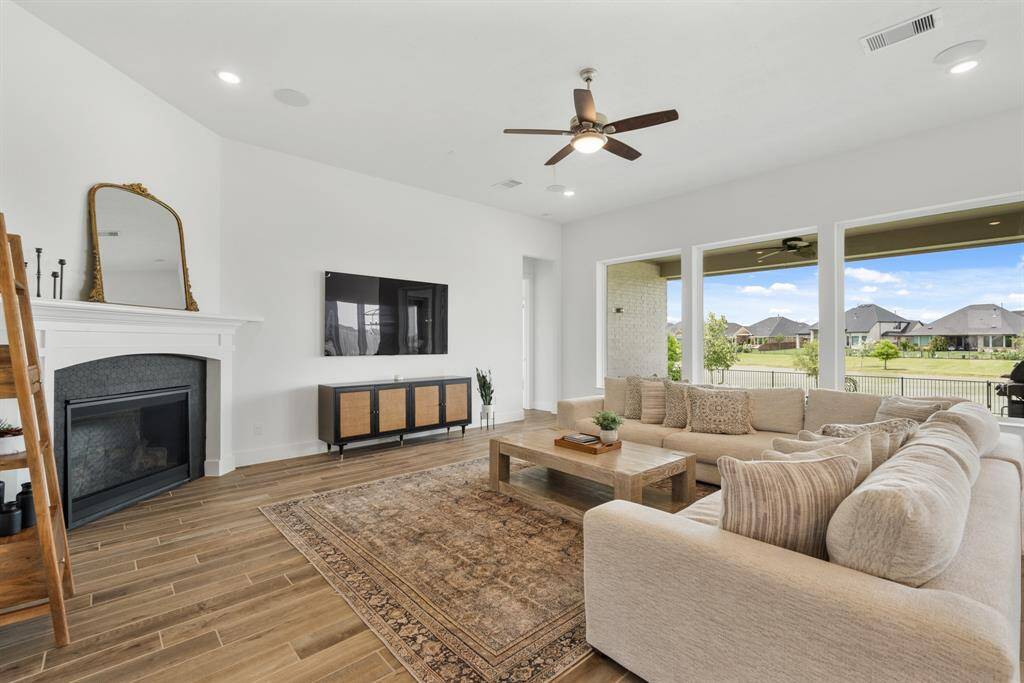 Step into the expansive living room, where soaring ceilings enhance the light and airy ambiance. Three picture windows offer serene views of the yard, while recessed lighting, a ceiling fan, and built-in wired speakers combine comfort and modern convenience.
