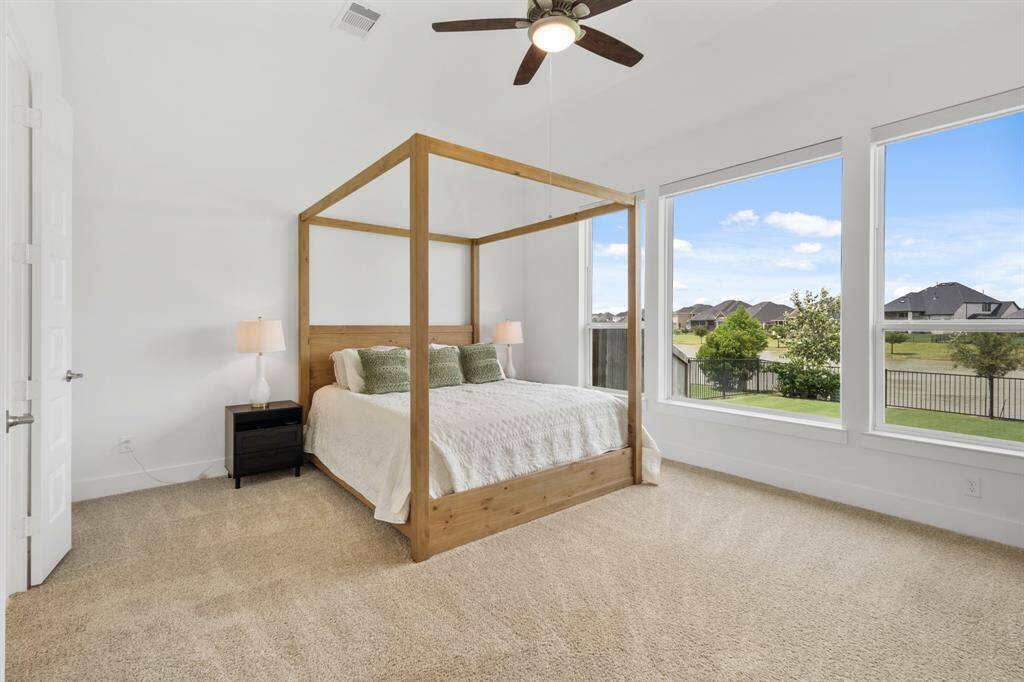 Retreat to the spacious primary bedroom, where three large windows frame tranquil views of the backyard and water beyond. Soft Charming Tones carpet underfoot adds comfort and warmth to this serene, light-filled haven.