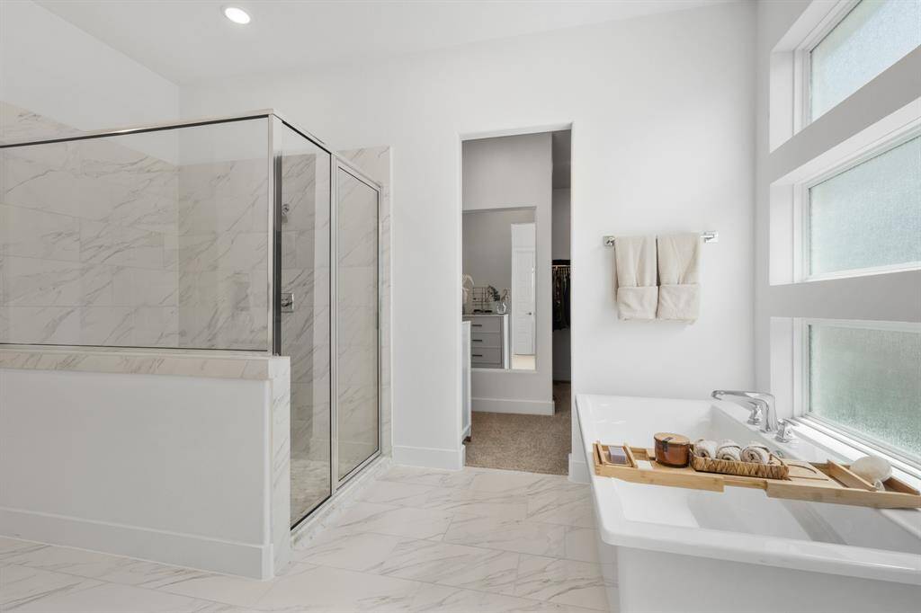 Step into the beautifully appointed walk-in shower, featuring elegant Florentine Carrara tile with a matte finish laid in a 1/3 offset pattern. Underfoot, the Presario Lumen White honed hexagonal tile adds a subtle touch of luxury and texture, perfectly complementing the spa-like atmosphere.
