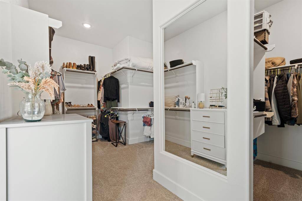 The massive walk-in closet is a dream come true, featuring built-in shelving, ample hanging space, and a full-length mirror seamlessly integrated into the wall. Plush carpet underfoot adds comfort and warmth—an ideal space to organize and enjoy your year-round wardrobe.
