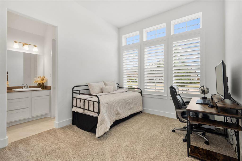 This charming guest bedroom, located near the front of the home, features three large windows adorned with plantation shutters that frame serene views of the front yard. Thoughtfully designed for comfort, it shares a stylishly appointed bathroom with the adjacent guest bedroom.