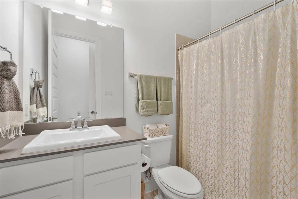 This guest bathroom showcases painted JKraft cabinetry in a crisp Studemont Pure White finish, complemented by sophisticated Grey Expo Quartz countertops with a sleek square edge. Chrome Ashlyn family fixtures add a polished, contemporary touch to the space.