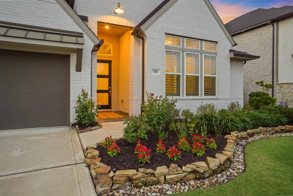 The front entryway includes a recessed porch with high ceilings and a modern front door with glass paneling. A stone-bordered walkway leads to the entrance, enhancing accessibility and curb appeal.