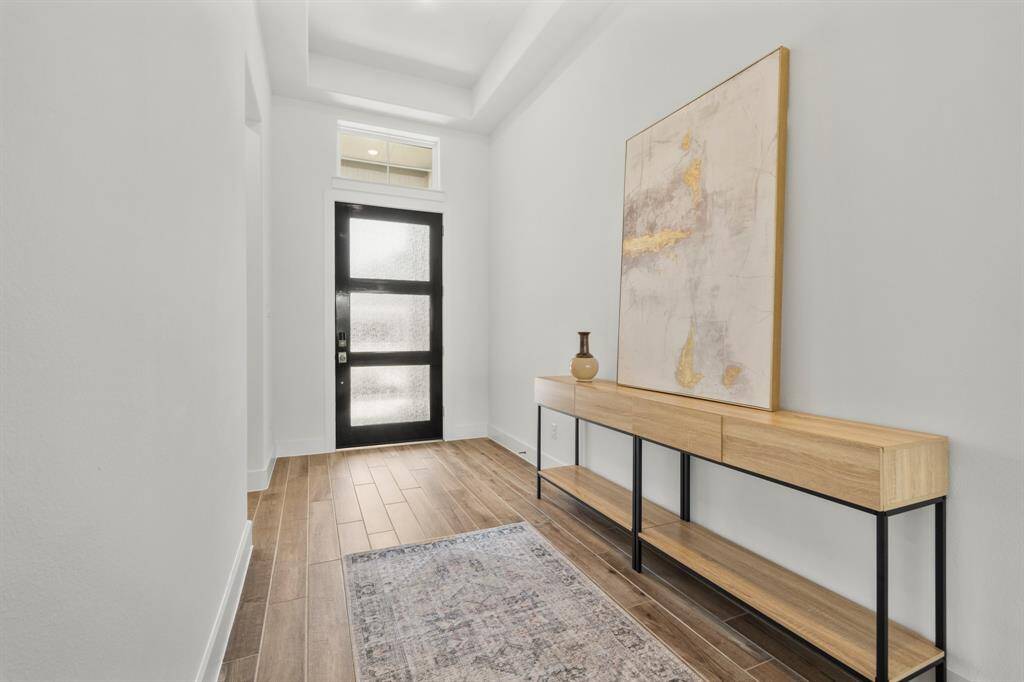An alternate perspective reveals the elegant tray ceiling and crisp architectural lines that add depth and dimension. The walls, painted in Snowbound and accented with Pure White trim, offer a fresh, timeless canvas. A spacious entry wall serves as the perfect backdrop for an entryway table, statement mirror, or artwork—blending function with style right from the start.