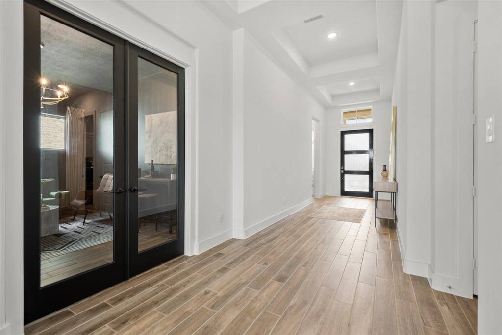 Just off the entry, discover a versatile private study—currently styled as a social room—framed by striking glass double doors with a bold dark trim. This space offers both privacy and style, making it ideal for work, relaxation, or entertaining.