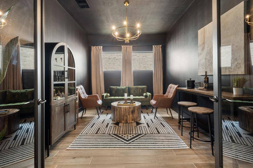 Step into this richly hued social room, where deep tones create a cozy, moody ambiance. A striking gold chandelier serves as a dramatic focal point, adding a touch of glamour and sophistication to the space.